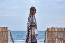 Mujer joven parada cerca de la playa, envuelta en manta, Odessa, Óblast de Odessa, Ucrania, Europa - foto de stock