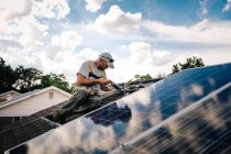 Workman installing solar panels on roof of house — Stock Photo