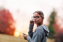 Retrato de menina com fones de ouvido e smartphone no jardim — Fotografia de Stock