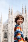 Retrato de niño mirando por encima del hombro en la plaza de la Catedral de Milán, Milán, Lombardía, Italia - foto de stock