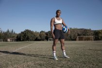 Porträt einer Frau, die Fußball hält und in die Kamera blickt — Stockfoto