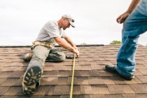 Dois trabalhadores no telhado, preparando-se para instalar painéis solares, visão de baixo ângulo — Fotografia de Stock