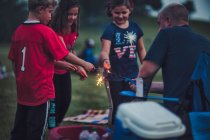 Father lighting sparklers for group of children — Stock Photo