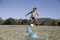 Jovem mulher driblando futebol em campo de futebol — Fotografia de Stock