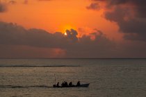 Paisaje marino con barco de pesca con siluetas al atardecer, Zanzíbar, Tanzania, África - foto de stock