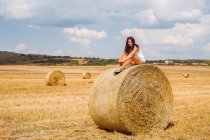 Woman sitting on top of hay bale — Stock Photo