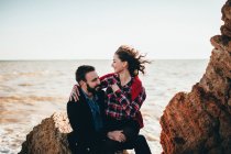 Romántica pareja adulta sentada en la roca de la playa, Óblast de Odesa, Ucrania - foto de stock
