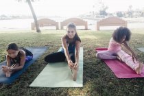 Tre studentesse che praticano yoga posano sul campo sportivo scolastico — Foto stock