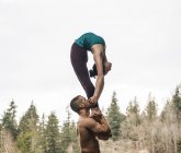 Couple practicing acroyoga with forest at background — Stock Photo