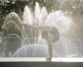 Дівчина-підліток біля фонтану балансує на руках — стокове фото