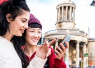 Две молодые стильные женщины смотрят на смартфон, Лондон, Великобритания — стоковое фото
