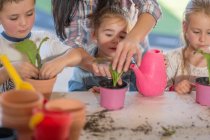 Mitte erwachsene Frau hilft kleinen Kindern bei der Gartenarbeit — Stockfoto