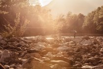 Рыбак, бросающий удочку в залитой солнцем реке, Мозирье, Брезовица, Словения — стоковое фото