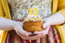 Jeune femme tenant cupcake célébrant — Photo de stock