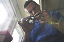 Male mechanic looking at car part in repair garage — Stock Photo