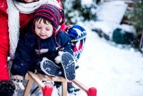 Mother and son in snow on toboggan — Stock Photo