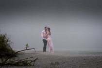 Wet romantic couple on misty beach — Stock Photo