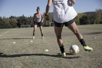 Jovens mulheres em campo de futebol jogando futebol — Fotografia de Stock