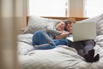 Друзья используют ноутбук на кровати — стоковое фото