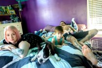 Famiglia e cane domestico sul letto in camera da letto — Foto stock