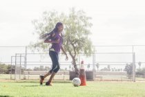 Teenage studentessa doing dribbling soccer ball practice on school sports field — Foto stock
