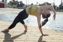 Mujer joven al aire libre, en posición de yoga, Long Beach, California, Estados Unidos - foto de stock