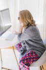Молода жінка сидить за столом у вітальні і використовує комп'ютер — стокове фото