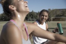 Mulheres sentadas em campo de futebol com garrafa de água — Fotografia de Stock