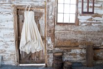 Vintage wedding dress hanging on barn door — Stock Photo