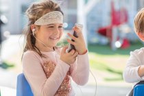 Молода дівчина використовує смартфон у навушниках — стокове фото