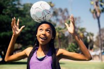 Adolescente estudante jogador de futebol balanceamento bola na cabeça no campo de esportes da escola — Fotografia de Stock