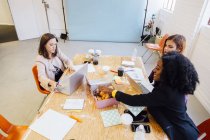 Колеги на офісному столі обмінюються пончиками — стокове фото