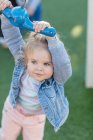 Девочка в детском саду, держит веревку на детской площадке качели в саду — стоковое фото