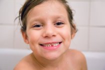 Портрет дівчини з відсутнім зубом у ванні, дивлячись на камеру посміхаючись — стокове фото