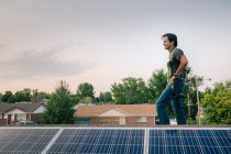 Trabalhador de pé no telhado, a instalação de painéis solares — Fotografia de Stock