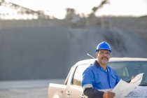 Portrait of quarry worker in quarry, holding document — Stock Photo