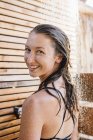 Portrait of young woman smiling at camera in outdoor shower — Stock Photo