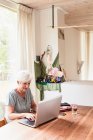 Старша жінка сидить за столом, використовуючи ноутбук — стокове фото