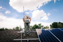 Workman instalação de painéis solares no telhado da casa, vista traseira — Fotografia de Stock