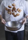 Cropped view of chef tossing doughnuts and sugar in mixing bowl — Stock Photo