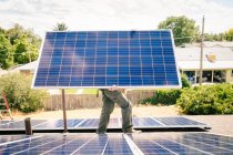 Workman installing solar panels on roof of house, carrying solar panel — Stock Photo