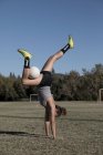 Mujeres en campo de fútbol haciendo handstand con fútbol - foto de stock