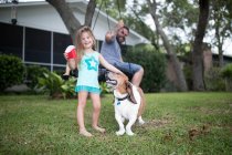 Отец и дочь в саду с собакой — стоковое фото