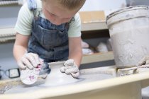 Хлопчик формує глину на гончарному колесі — стокове фото
