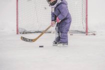 Jovencita jugando hockey sobre hielo, preparándose para golpear el disco, sección media - foto de stock