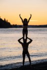 Пара практикующих йогу на пляже на закате — стоковое фото