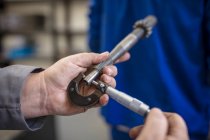 Mani del meccanico di auto maschile che tiene parte auto in garage di riparazione — Foto stock