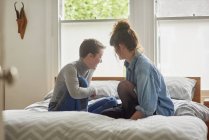 Two young women sitting and chatting on bed — Stock Photo
