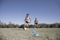 Duas jovens mulheres driblando bolas de futebol — Fotografia de Stock