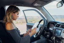 Junge Frau im Auto schaut auf digitales Tablet, mexikanischen Hut, utah, usa — Stockfoto